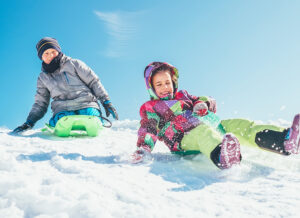 Children sledding down a snowy hill, laughing and enjoying the winter activity.